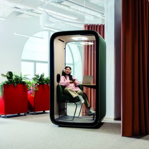 Dark Framery One pod beside office workstations