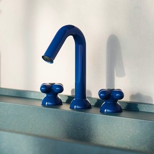 Red arched spout of an I Balocchi tap seen side on above the basin