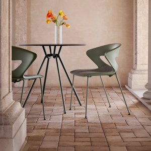 Ten Kicca chairs piled on the black KC17 trolley beside a store cupboard door