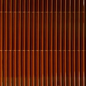 Light raking across the ribbed ceramic profile of a Rombini wall